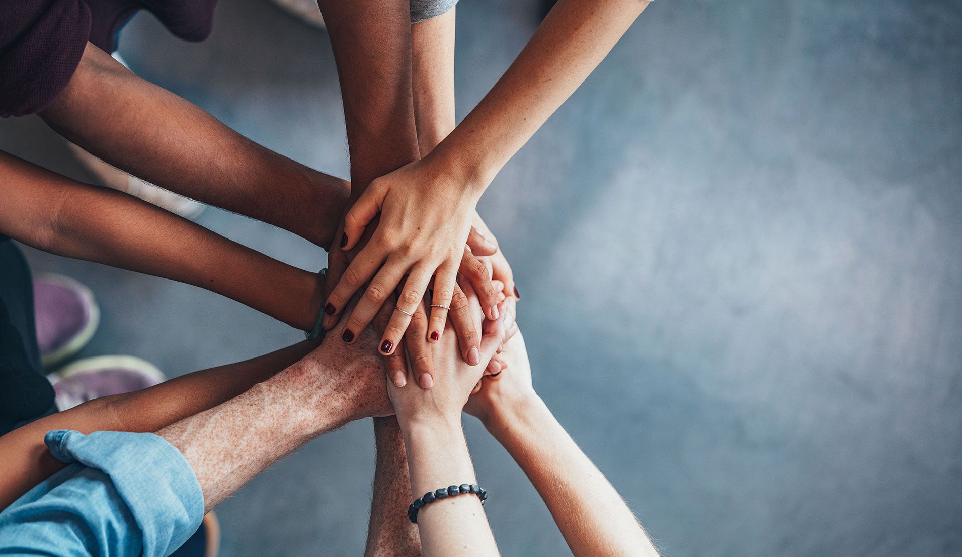 Fotka na ruce studentů, které mají položené na sebe, pohled ze shora.